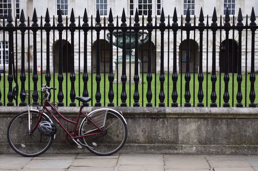 Dark red bicycle leaning against railings outside King's College Cambridge
